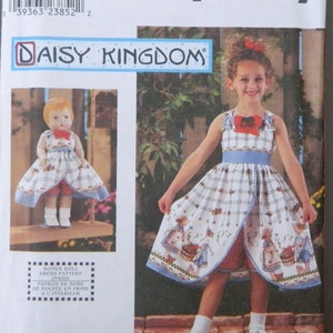 Puede incluir: Patrón de costura Simplicity 9166 para un vestido de niña y un vestido de muñeca a juego. El patrón presenta un vestido con estampado de cuadros azules y blancos, un lazo rojo y una faja azul. Se ve el logo de Daisy Kingdom.