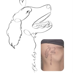 Op de afbeelding: Een zwarte lijntekening van een hond in profiel met een klein hartje boven de kop en de naam Charles in cursief schrift eronder. Het ontwerp is ook afgebeeld als tatoeage op een zij, uitgevoerd in dezelfde doorlopende lijnstijl.
