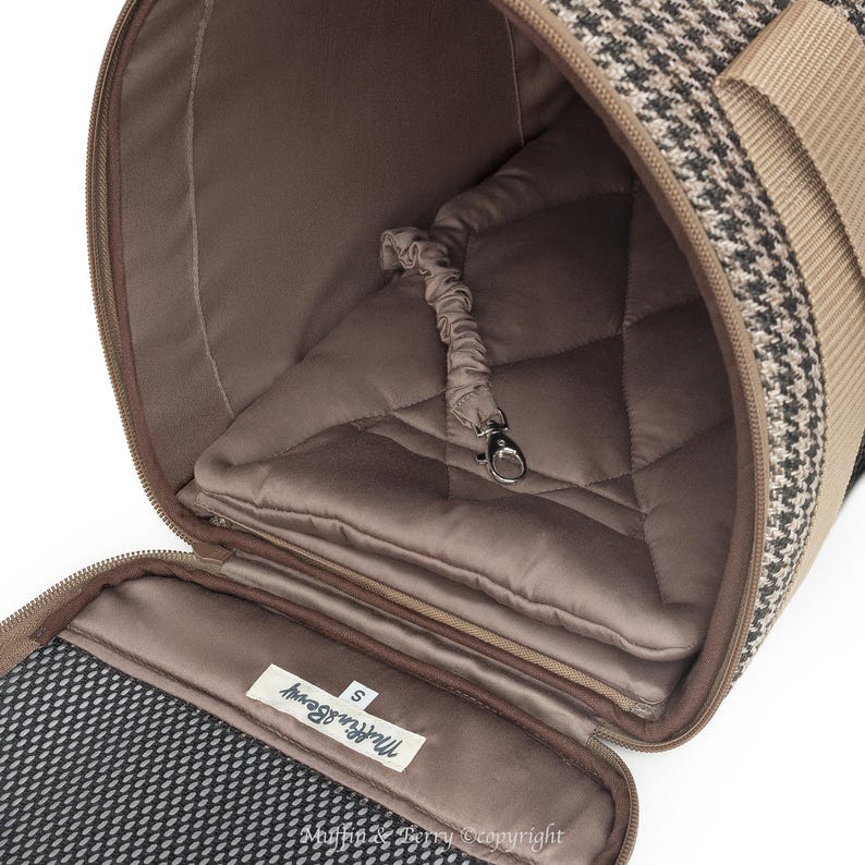Puede incluir: Un transport&iacute;n para mascotas de tweed marr&oacute;n y negro con un forro acolchado marr&oacute;n y un accesorio de correa. El transport&iacute;n est&aacute; abierto y la etiqueta dice "The Furry Beauty" con la talla "S" impresa debajo.