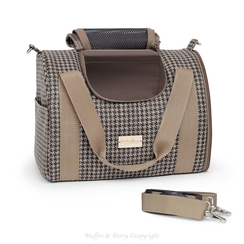 Puede incluir: Un transport&iacute;n para mascotas de color marr&oacute;n y beige con estampado de pata de gallo, con una parte superior de malla negra y un bolsillo con cremallera marr&oacute;n. El transport&iacute;n tiene dos correas marrones y una correa de hombro desmontable. El transport&iacute;n tiene una etiqueta dorada con el texto "Petlife" en ella.