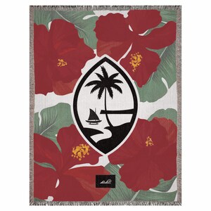 K&ouml;nnte beinhalten: Eine gewebte Wolldecke mit einem Muster aus roten Hibiskusbl&uuml;ten und dem Wappen von Samoa in der Mitte. Das Wappen ist schwarz-wei&szlig; und zeigt eine Palme, ein Segelboot und einen Strand.