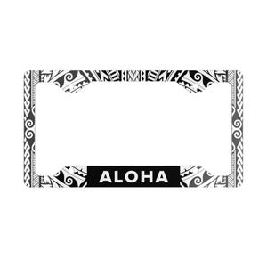 Puede incluir: Marco de matrícula en blanco y negro con un diseño tribal polinesio. La palabra "ALOHA" se muestra en letras blancas sobre un fondo negro en la parte inferior. El marco tiene forma rectangular.