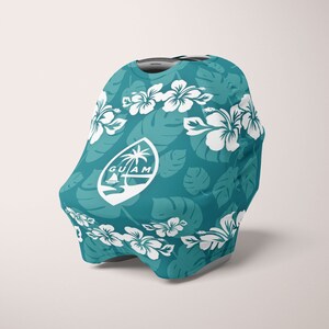 May include: A teal baby car seat cover featuring a white floral and leaf pattern. The cover has a white emblem with a palm tree, boat, and the word "GUAM". The design includes white hibiscus flowers and tropical leaves.