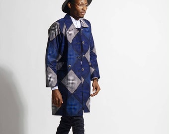Op de afbeelding: Een jas met lange mouwen voorzien van een blauw en wit geometrisch ruitpatroon met een herhalend optisch illusie-effect. De jas heeft een gestructureerde kraag, een knoopsluiting aan de voorzijde en wordt gecombineerd met een donkere broek, zwarte laarzen en een zwarte fedora hoed.