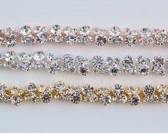 May include: Three rows of clear rhinestone trim with different colored metal settings. The top row has a rose gold setting, the middle row has a silver setting, and the bottom row has a gold setting.