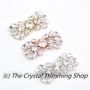 May include: Three crystal embellishments in gold, rose gold, and silver. Each embellishment is made up of multiple crystal rhinestones in a cluster design. The embellishments are perfect for adding a touch of sparkle to any project.