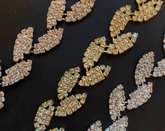 May include: Three rows of rhinestone chains with a zig-zag pattern. The chains are made of silver, gold, and rose gold.