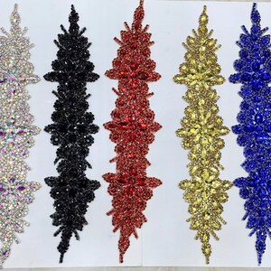 May include: Seven rows of decorative trim with various colored rhinestones. The trim is arranged in a vertical line with each row featuring a different color: clear, silver, black, red, gold, blue, and copper.