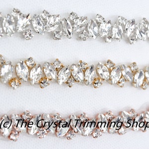 May include: Three rows of clear crystal rhinestone trim with different colored settings. The top row has silver settings, the middle row has gold settings, and the bottom row has rose gold settings.  (c) The Crystal Trimming Shop