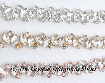 May include: Three rows of clear crystal rhinestone trim with different colored settings. The top row has silver settings, the middle row has gold settings, and the bottom row has rose gold settings.  (c) The Crystal Trimming Shop