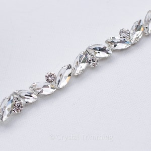 May include: A silver trim with clear crystal rhinestones in a marquise shape. The rhinestones are arranged in a staggered pattern.