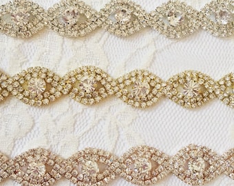 May include: Three rows of silver, gold, and rose gold rhinestone trim with a repeating pattern of oval shapes. Each oval is made of small rhinestones surrounding a larger rhinestone in the center.