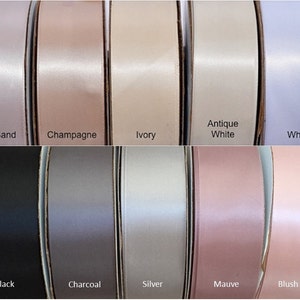 Op de afbeelding: Een selectie van 10 verschillende kleuren satijnen lint, waaronder roze zand, champagne, ivoor, antiek wit, wit, zwart, antraciet, zilver, mauve en blush roze.