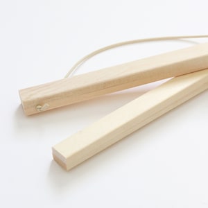 Peut inclure: Deux supports de poster en bois avec une ficelle blanche attachée. Les supports sont en bois naturel et sont conçus pour tenir des affiches ou des œuvres d'art.
