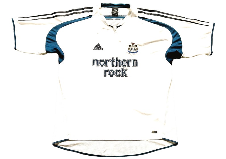 May include: White football shirt with black and blue accents. The shirt has the Adidas logo, the Newcastle United crest, and the text "northern rock" on the front.