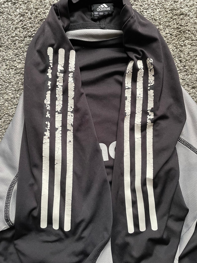 May include: Black long-sleeve shirt with white stripes on the sleeves. The shirt has the Adidas logo on the front.