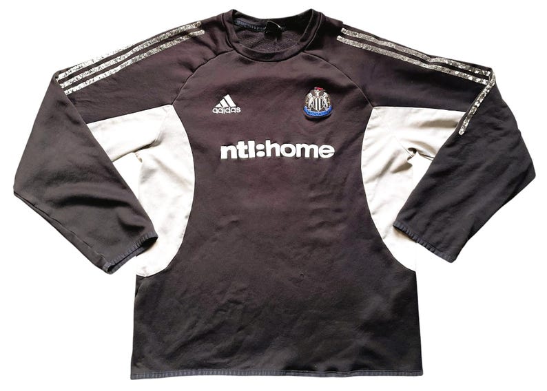 May include: Black and white long-sleeved football shirt with the Adidas logo, a team crest, and the text "ntl:home".