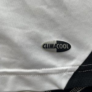 Pode incluir: Close-up de uma camisa atl&eacute;tica branca com um design em preto e branco. A camisa apresenta o logotipo "CLIMACOOL" em preto e branco. O tecido tem uma apar&ecirc;ncia texturizada.