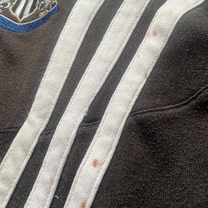 May include: Close-up of a black and white striped fabric with brown stains. The fabric has three white stripes with a black background.