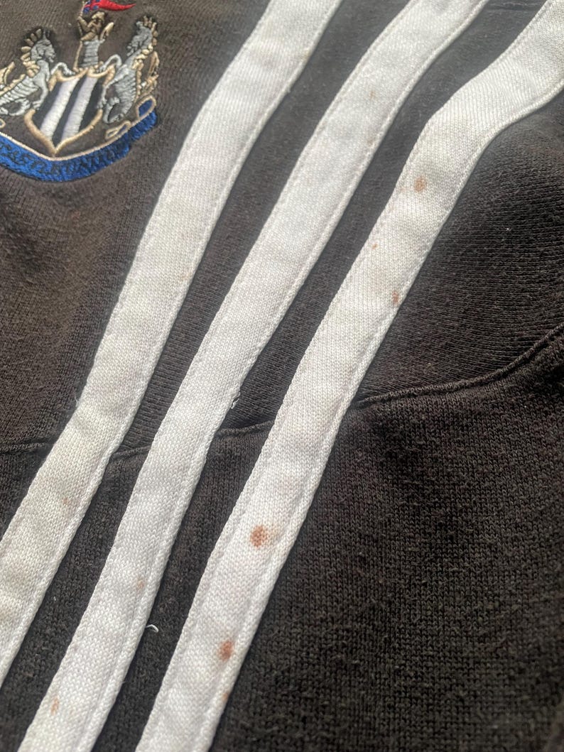 May include: Close-up of a black and white striped fabric with brown stains. The fabric has three white stripes with a black background.