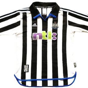 May include: A white and black striped football shirt with blue trim. The shirt has the Adidas logo, the Newcastle United crest, and the NTL logo.