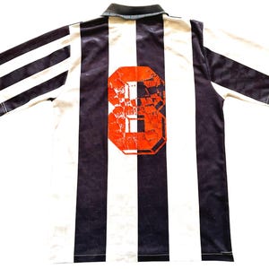 Pode incluir: Camisola de futebol branca e preta com um n&uacute;mero 8 vermelho nas costas.