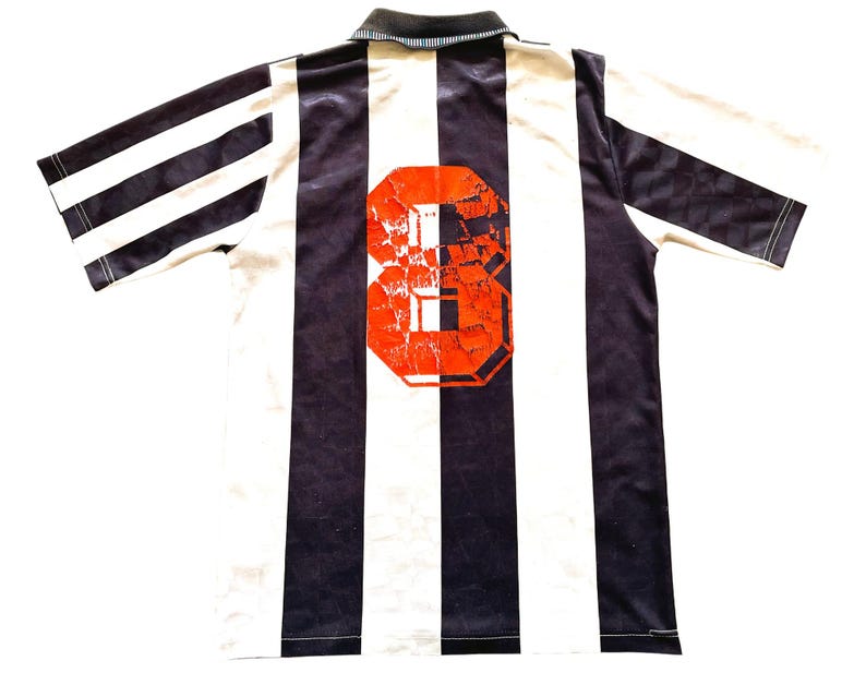 Pode incluir: Camisola de futebol branca e preta com um n&uacute;mero 8 vermelho nas costas.