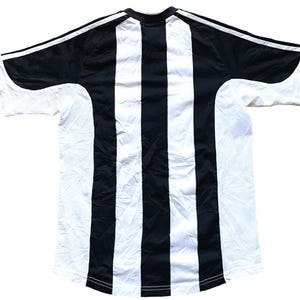 May include: Black and white striped soccer jersey with a crew neck and short sleeves.