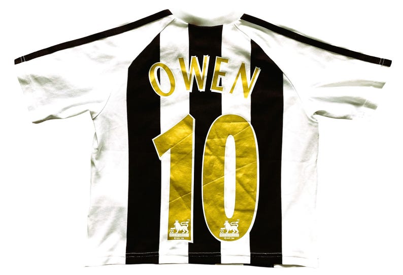 May include: White and black striped soccer jersey with the name "OWEN" and the number "10" in gold. The jersey has black stripes on the shoulders and the Premier League logo.