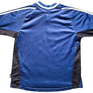 Op de afbeelding: Een blauw en zwart shirt met korte mouwen en een witte rand rond de hals.