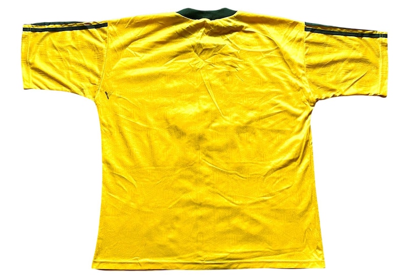 May include: A bright yellow short-sleeved jersey with a dark green collar and dark green stripes on the shoulders. The jersey is made of a lightweight, possibly athletic material, and is displayed against a white background.