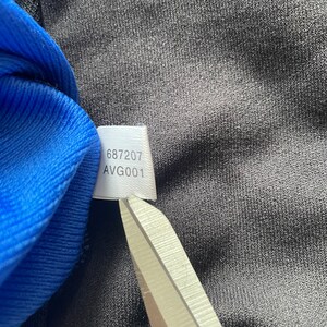 May include: A white tag with the numbers "687207" and the text "AVG001" printed on it.