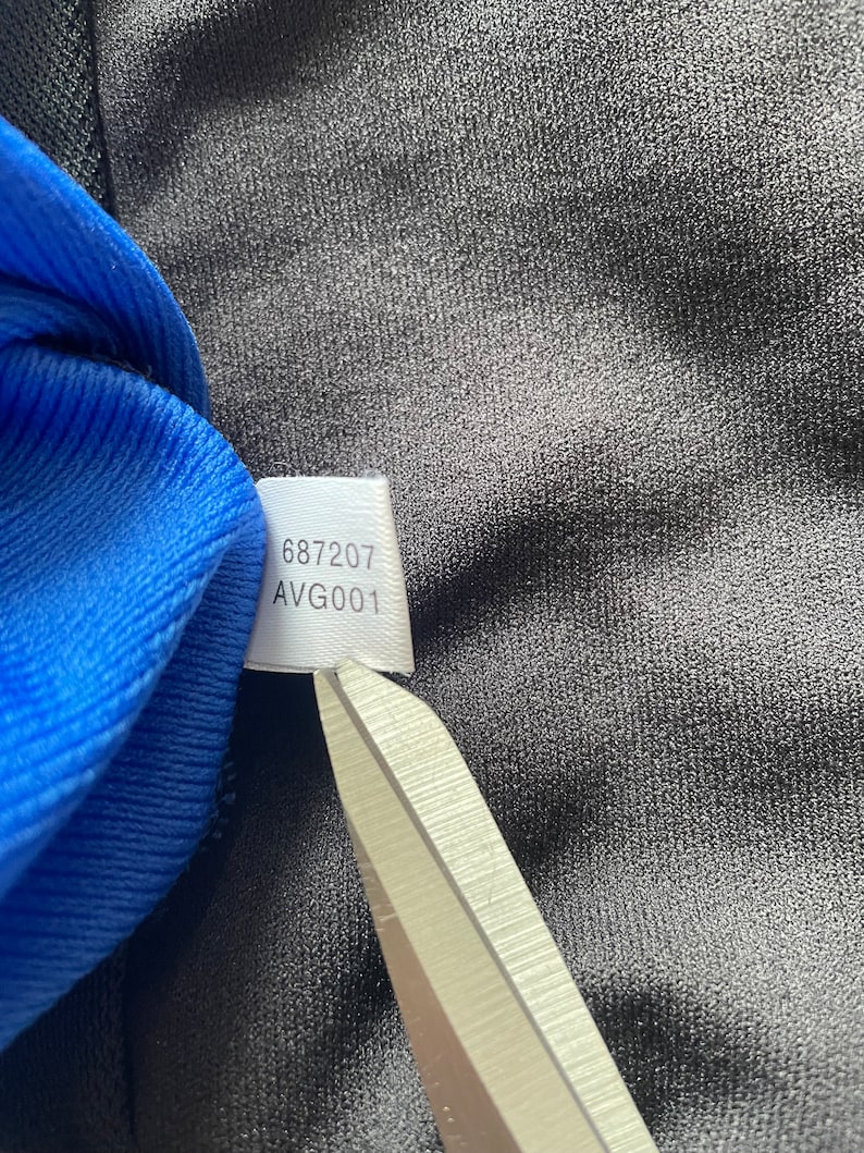 May include: A white tag with the numbers "687207" and the text "AVG001" printed on it.