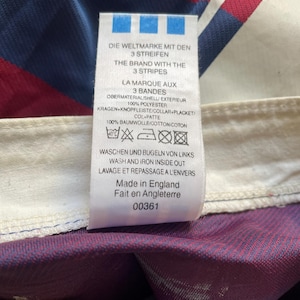 May include: A tag with text in multiple languages, including English, German, and French. The tag lists fabric composition as 100% polyester and 100% cotton. The tag also includes washing instructions and states "Made in England."
