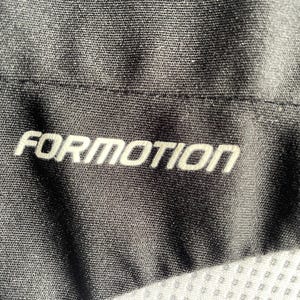 Pu&ograve; includere: Primo piano di tessuto nero con la scritta "FORMOTION" in bianco, centrata. Il tessuto ha un aspetto strutturato e le cuciture sono visibili. L'immagine &egrave; ben illuminata, evidenziando i dettagli del materiale.