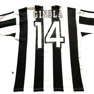 May include: A black and white striped soccer jersey with the name "CINOLA" and the number "14" on the back. The jersey has short sleeves with black and white stripes.