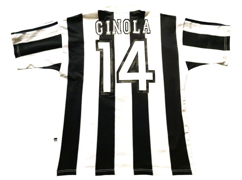 May include: A black and white striped soccer jersey with the name "CINOLA" and the number "14" on the back. The jersey has short sleeves with black and white stripes.