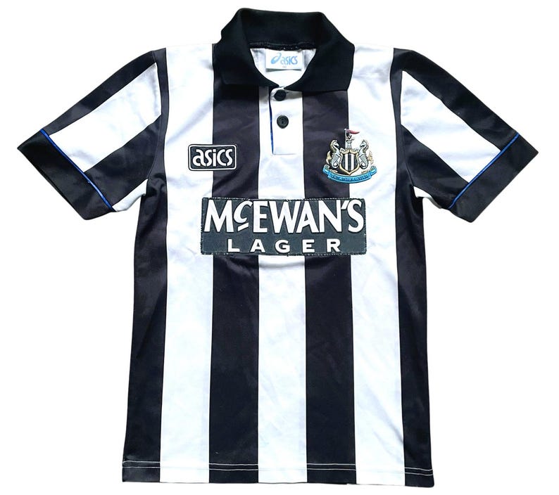 K&ouml;nnte beinhalten: Schwarz-wei&szlig; gestreiftes Fu&szlig;balltrikot mit schwarzem Kragen und &Auml;rmeln. Das Trikot zeigt das "Asics"-Logo, das "McEwan's Lager"-Logo und ein Teamwappen. Die &Auml;rmel haben blaue Paspeln.