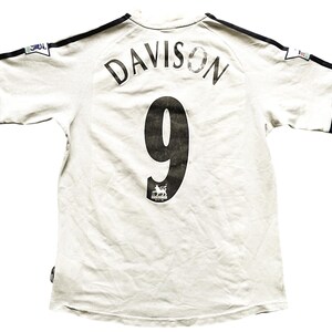 Puede incluir: Camiseta de f&uacute;tbol blanca con ribetes negros y el nombre "DAVISON" y el n&uacute;mero "9" en la espalda.