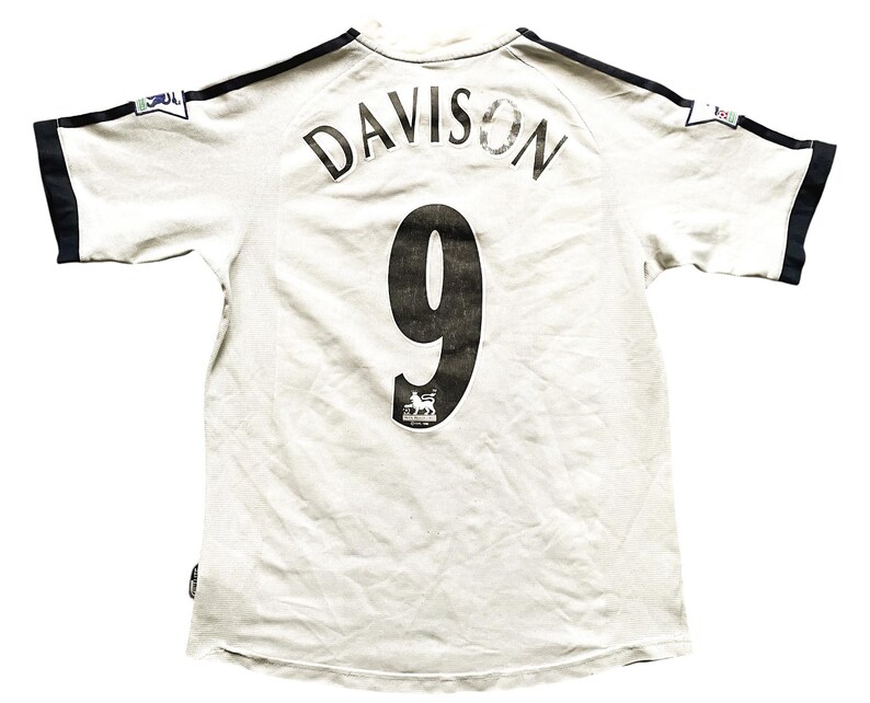 Puede incluir: Camiseta de f&uacute;tbol blanca con ribetes negros y el nombre "DAVISON" y el n&uacute;mero "9" en la espalda.