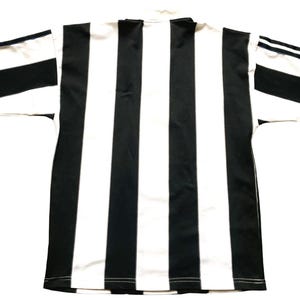 May include: Black and white striped jersey. The shirt has a classic design with vertical black stripes alternating with white stripes. The sleeves have black and white striped cuffs. The collar is white.