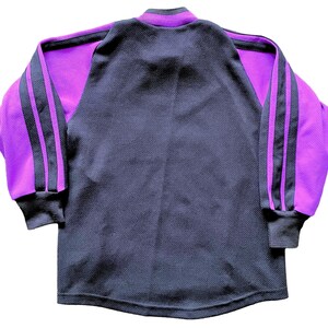 May include: A long-sleeved shirt with a black body and purple sleeves. The sleeves have two black stripes down the side.