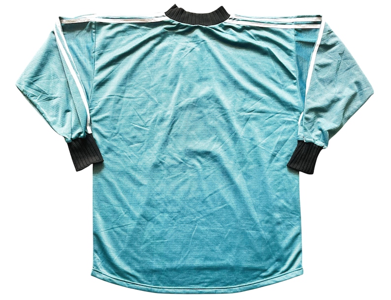 May include: A long-sleeved teal jersey with white stripes on the shoulders and sleeves. The cuffs and collar are black. The jersey is made of a soft, textured material.