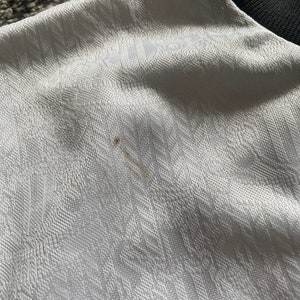 May include: White fabric with a textured pattern. The fabric has a small brown stain.