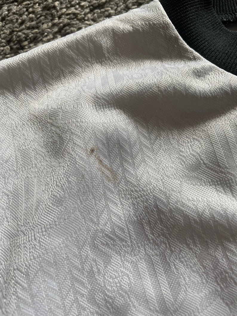 May include: White fabric with a textured pattern. The fabric has a small brown stain.