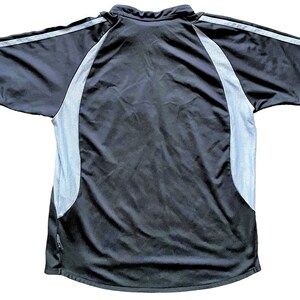 May include: Black short-sleeved shirt with white mesh panels on the sides and a white stripe on the sleeves.