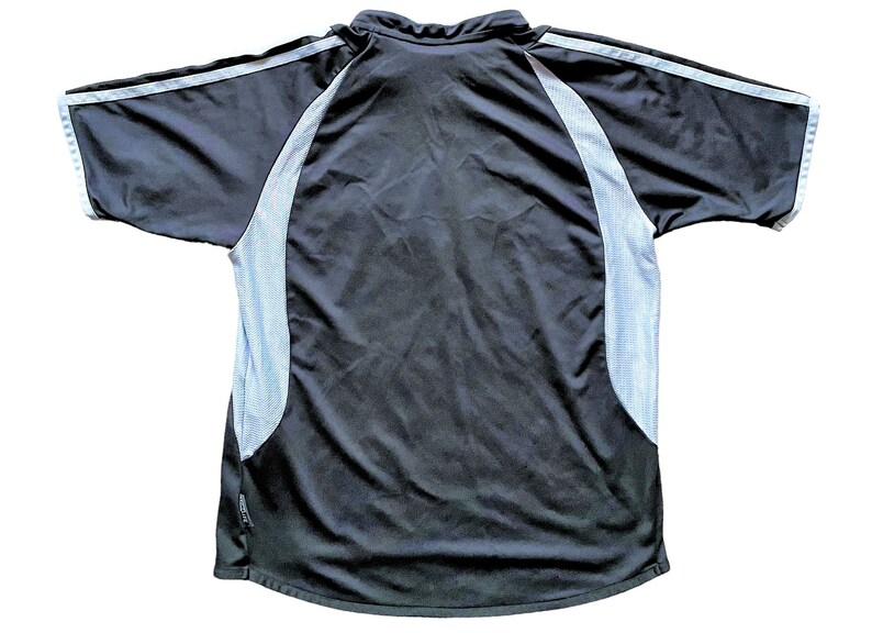 May include: Black short-sleeved shirt with white mesh panels on the sides and a white stripe on the sleeves.