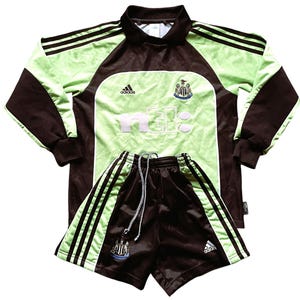 May include: A green and brown soccer jersey and shorts set with the Newcastle United logo and the word "nufc" on the front. The jersey is long-sleeved and has Adidas branding. The shorts have three white stripes on each side.