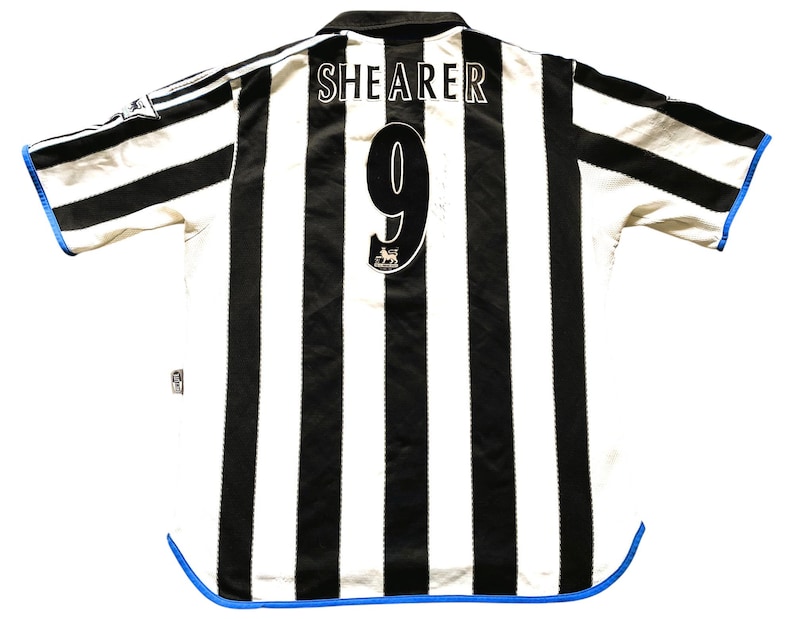Puede incluir: Camiseta de f&uacute;tbol a rayas blancas y negras con ribetes azules. La parte posterior de la camiseta tiene el nombre "SHERER" y el n&uacute;mero "9" impreso.