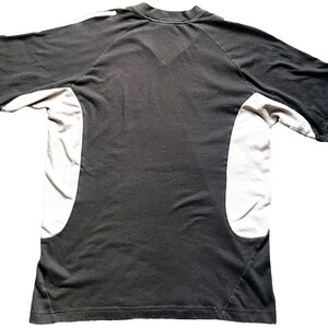 May include: Black short-sleeved t-shirt with white panels on the sides. The shirt has a crew neck and a relaxed fit.